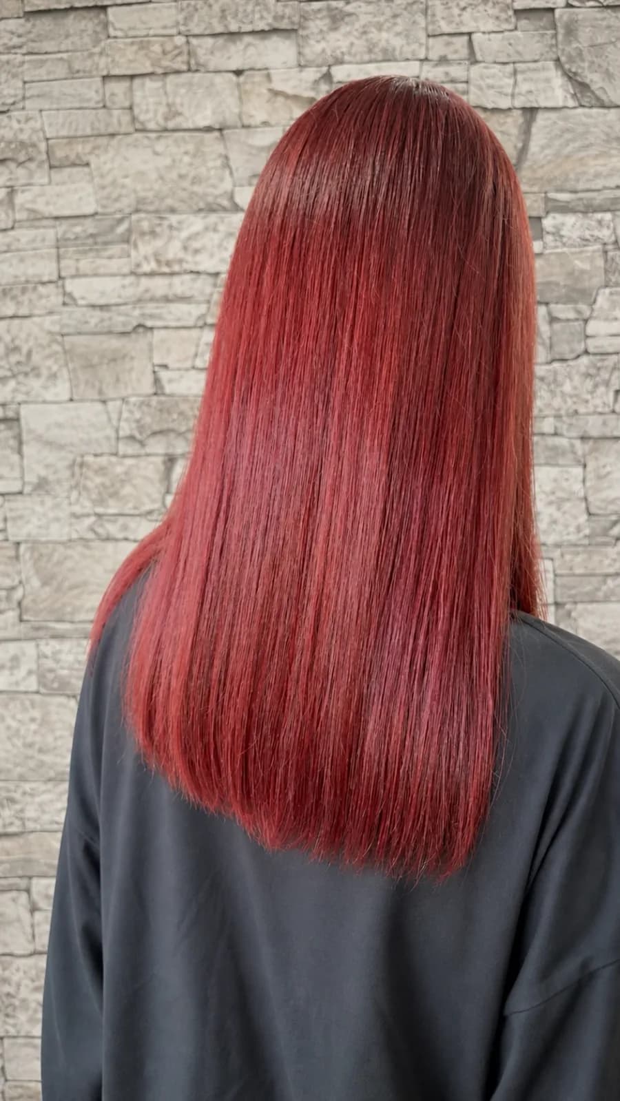 発色のよい赤にカラーしたストレートのロングヘアの後ろ姿